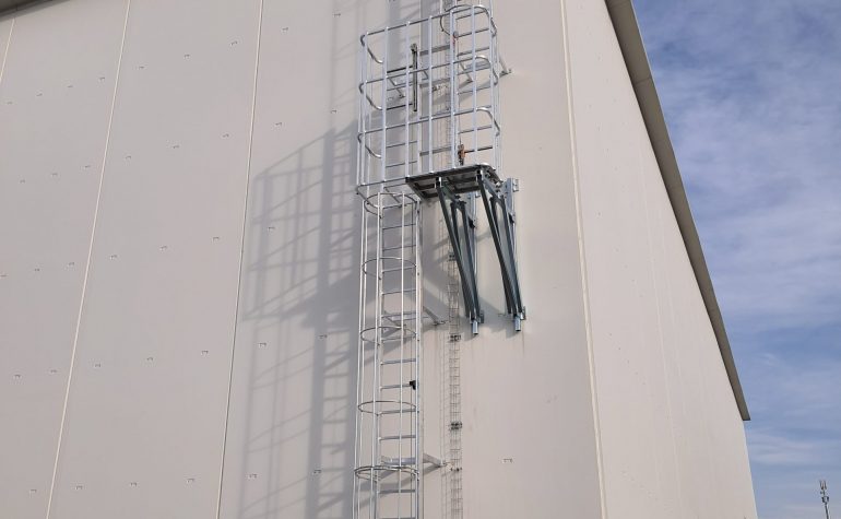Scala con gabbia di protezione dotata di ballatoio intermedio di riposo e linea vita verticale anticaduta.
